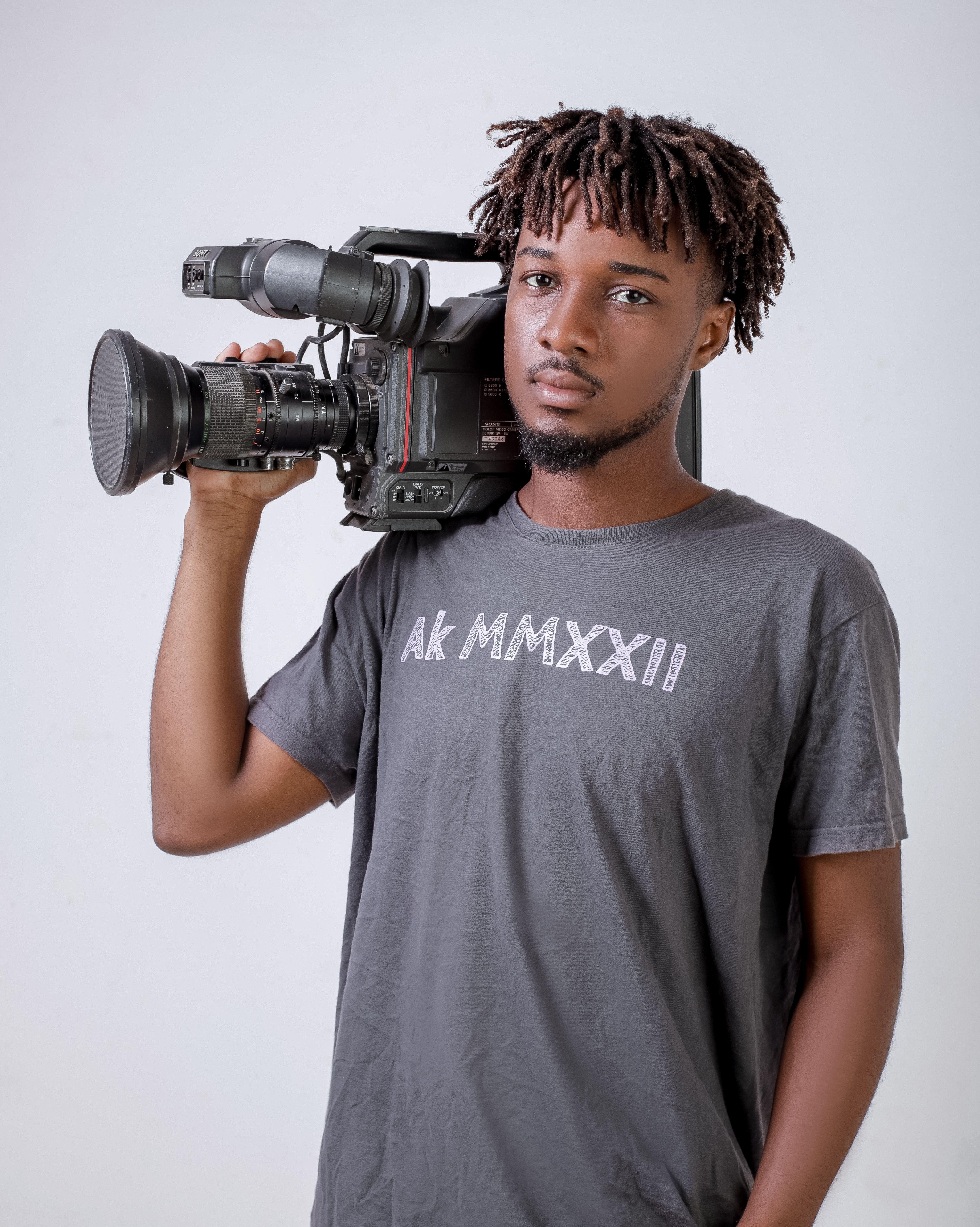 Confident man holding professional video camera, studio portrait.
