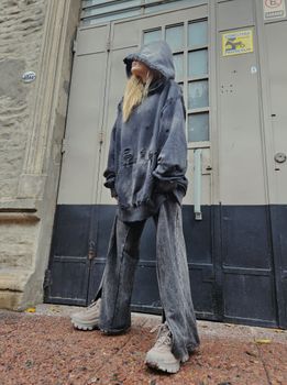 Stylish young woman in oversized hoodie stands against an urban doorway, showcasing modern streetwear fashion.