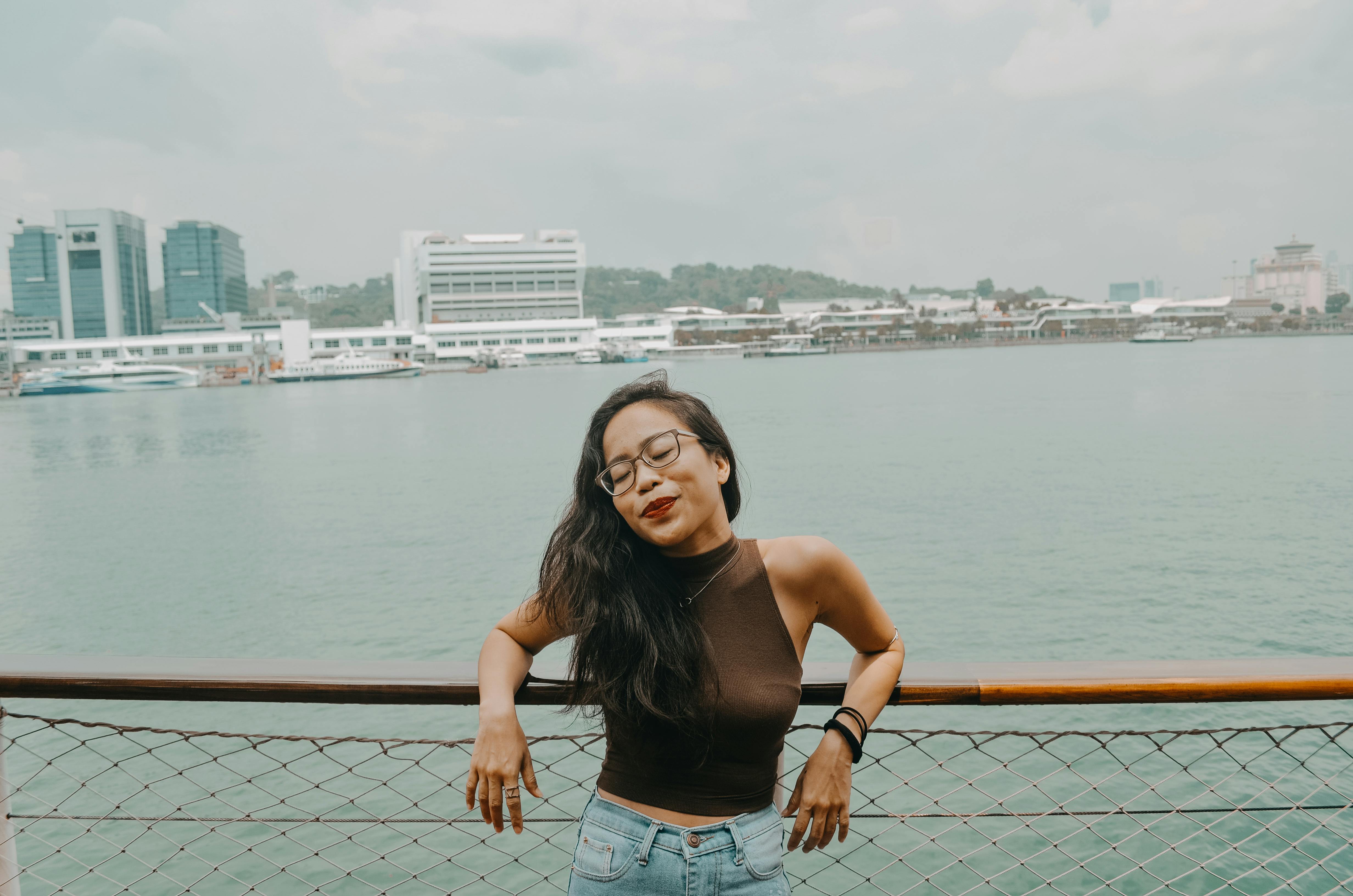 一位快乐的戴眼镜女人在码头海滨享受着宁静的时刻，拥抱这一天