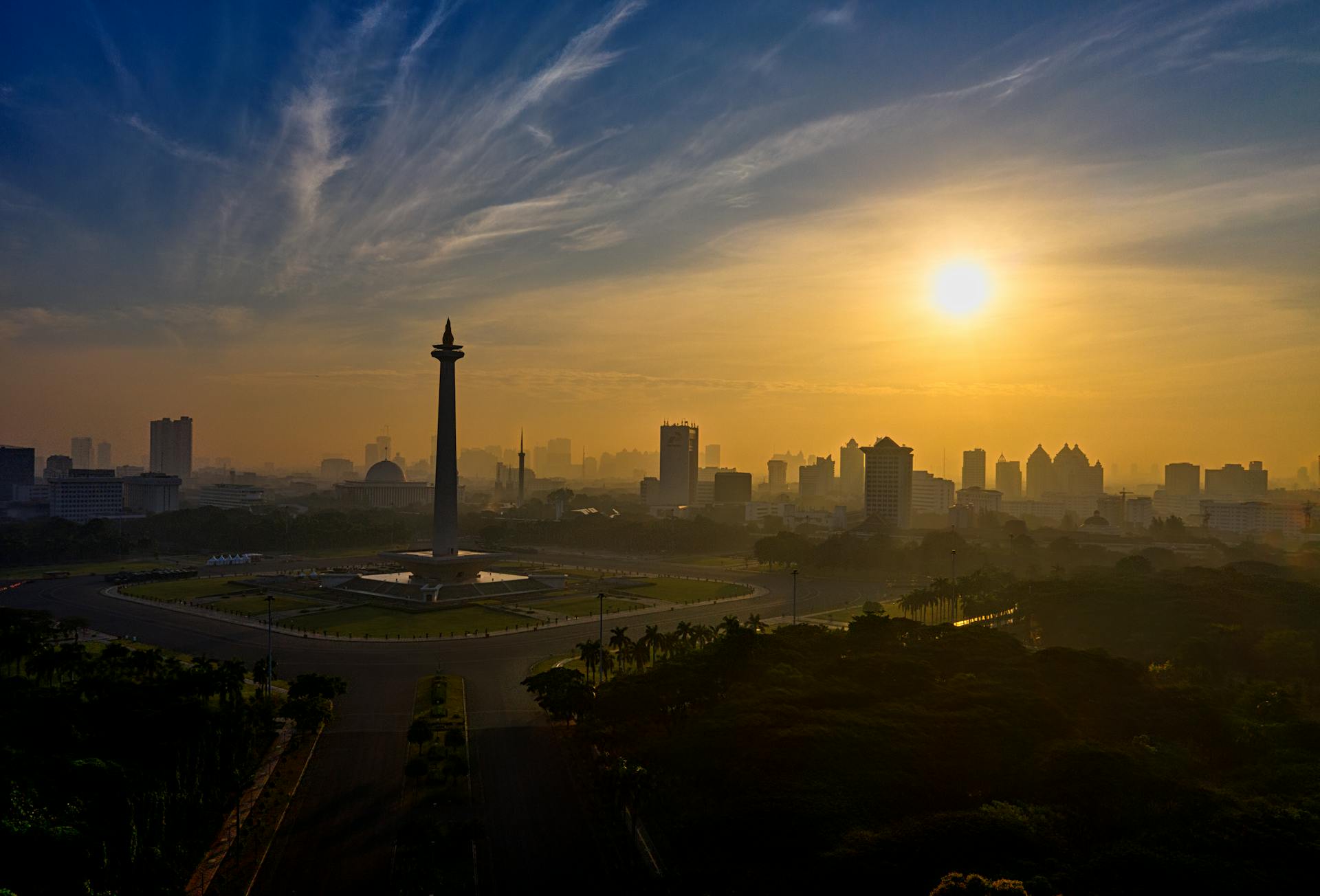 A breathtaking aerial view of Jakarta's skyline and National Monument at sunrise, showcasing cityscape beauty.