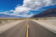 一条荒凉的直路在明亮的蓝天下，向沙漠景观延伸而去