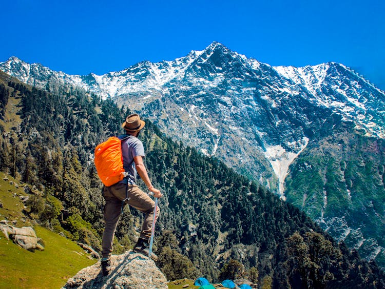 Man Wearing Blue Shirt Standing On Cliff While Watching Mountain