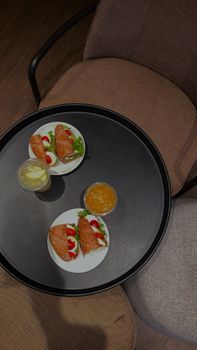 Flat lay of sandwiches and drinks on a circular tray atop a cozy chair.