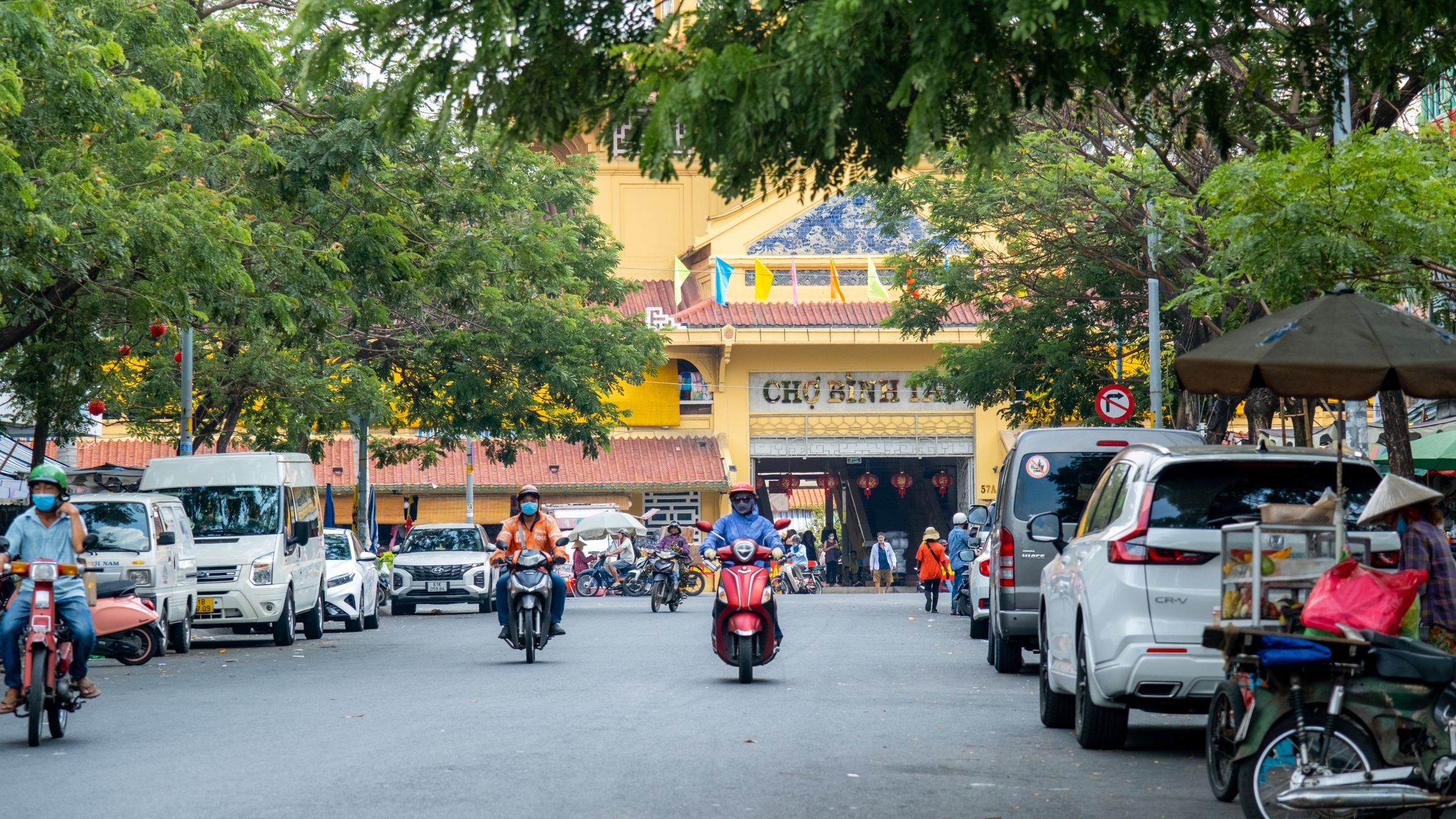 Motorcycles and cars traverse a vibrant street near Ben Thanh Market in Ho Chi Minh City.