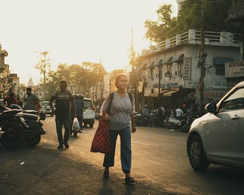 Free A busy city street with pedestrians and vehicles during sunset, creating a warm urban atmosphere. Stock Photo