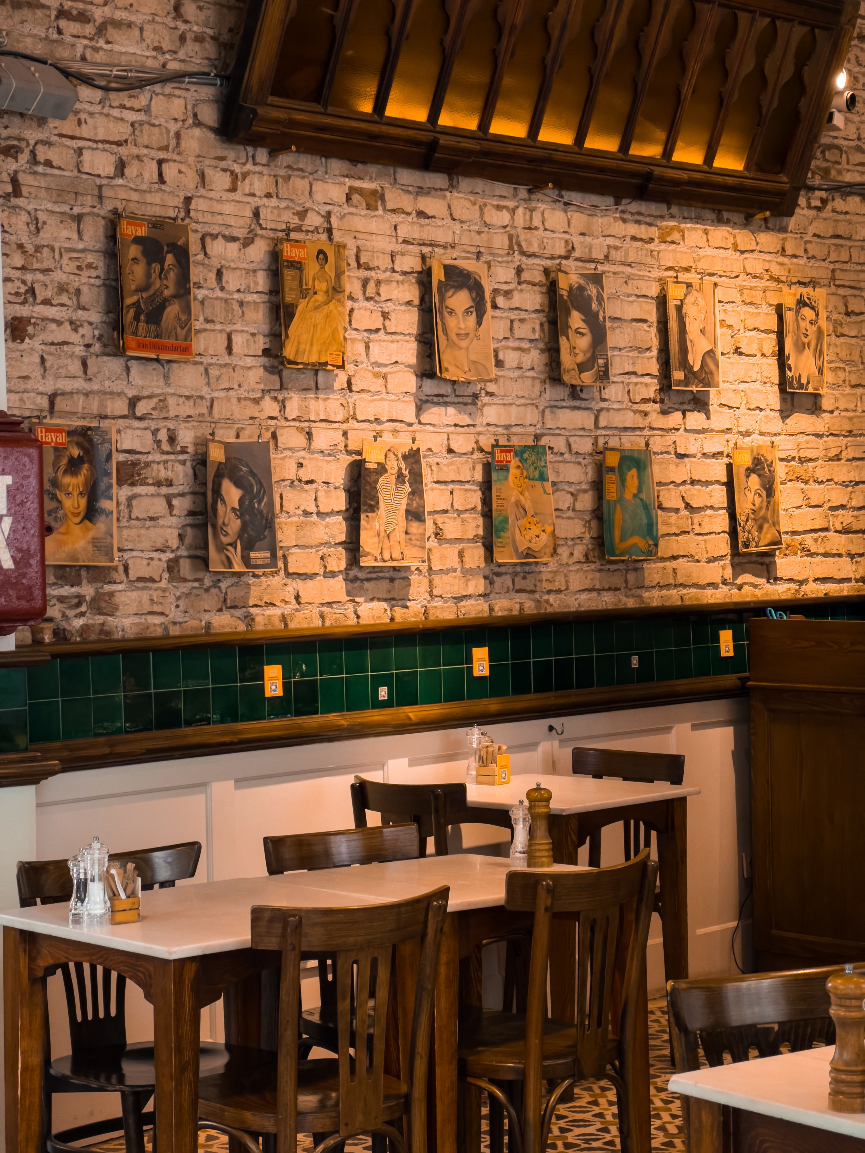 Warm café interior featuring vintage portraits on brick wall. Perfect ambiance for a quiet meal.