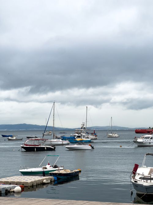 Free A serene coastal scene with moored boats and an overcast sky, ideal for travel themes. Stock Photo