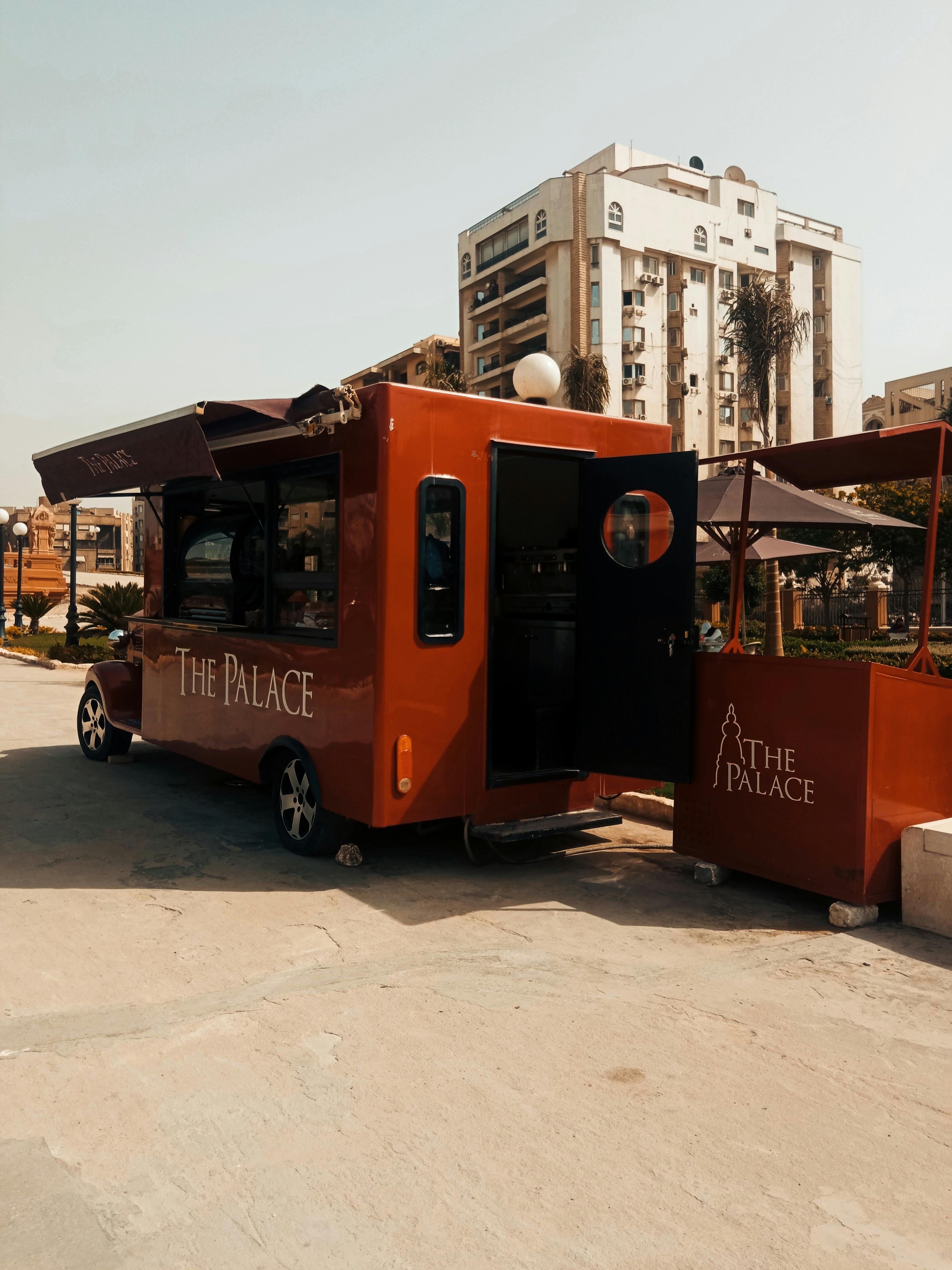 Red food truck named 'The Palace' parked in a city with skyscrapers.