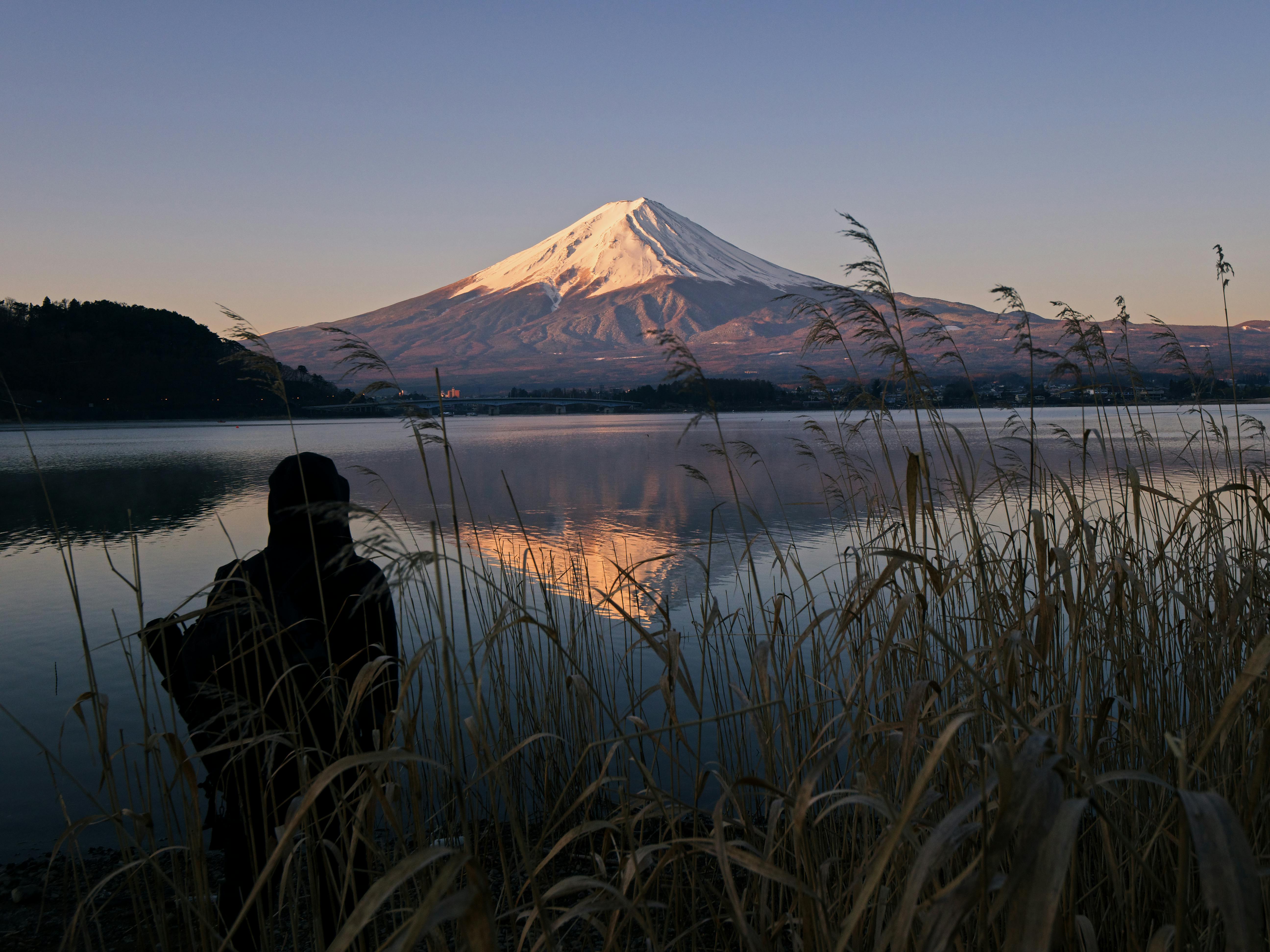 黄昏时分，一个人静静欣赏富士山倒映在平静水面上的宁静景色