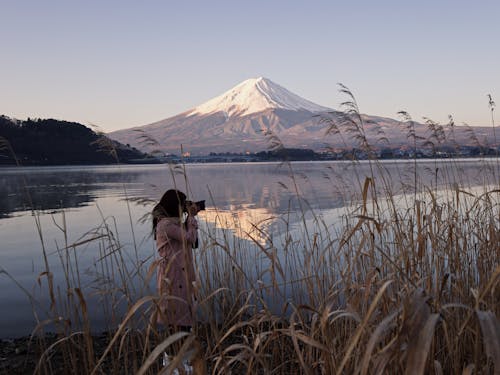 Woman Taking Picture Near Lake With View of Mount Fuji