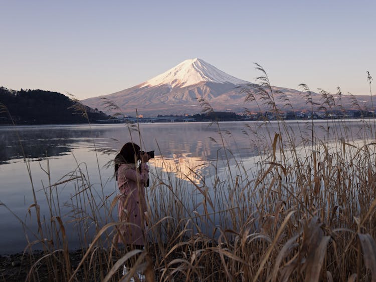 Woman Taking Picture Near Lake With View Of Mount Fuji