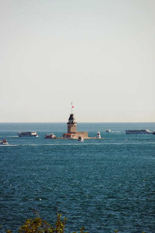 A lighthouse in the middle of the ocean with boats