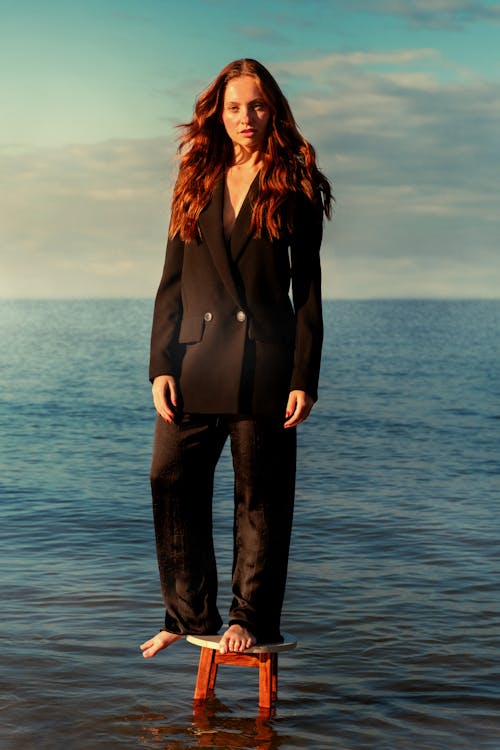 A woman in a black suit standing on a stool in the water