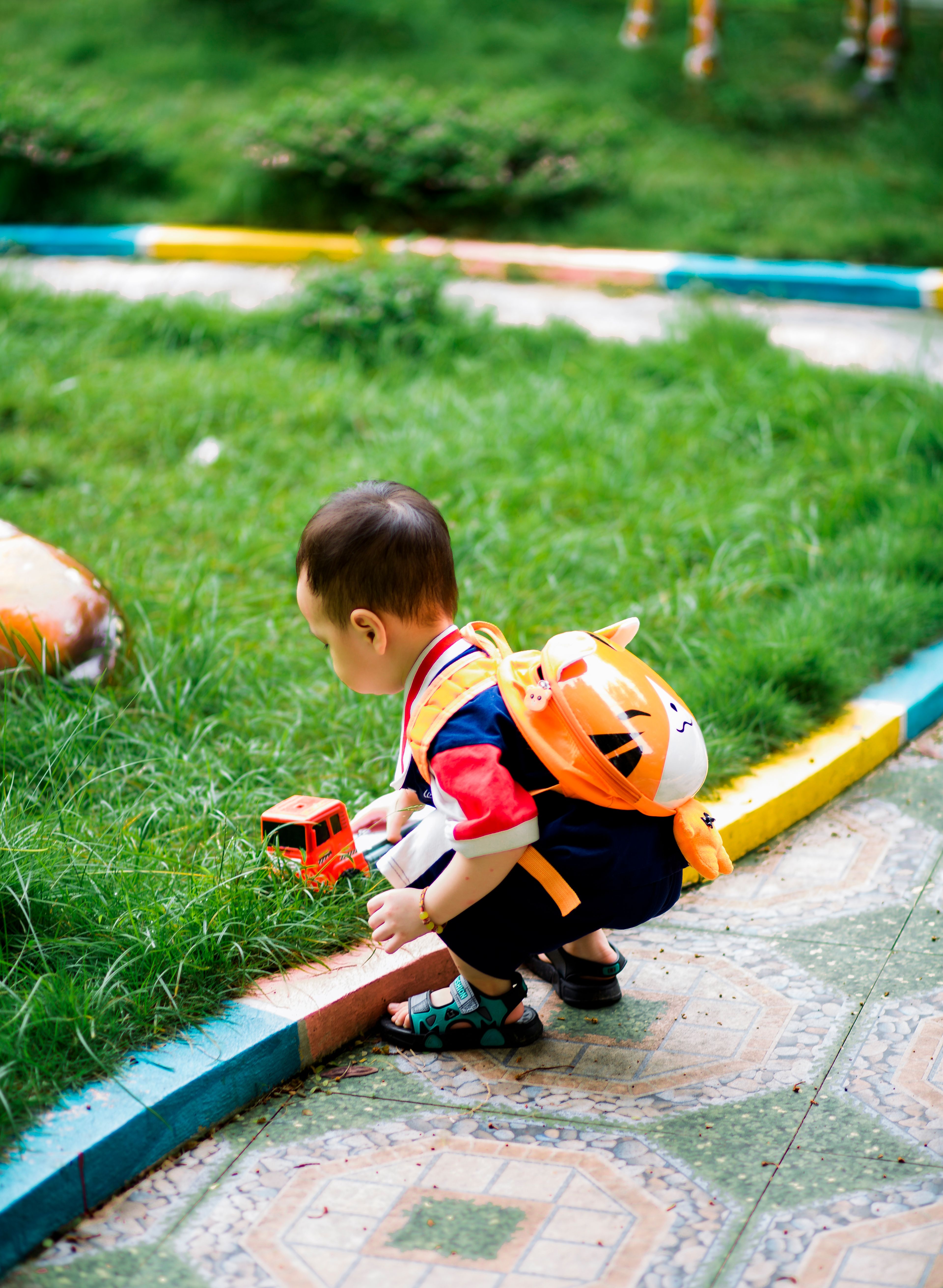 Young child enjoying outdoor play with a toy car in a colorful park setting.
