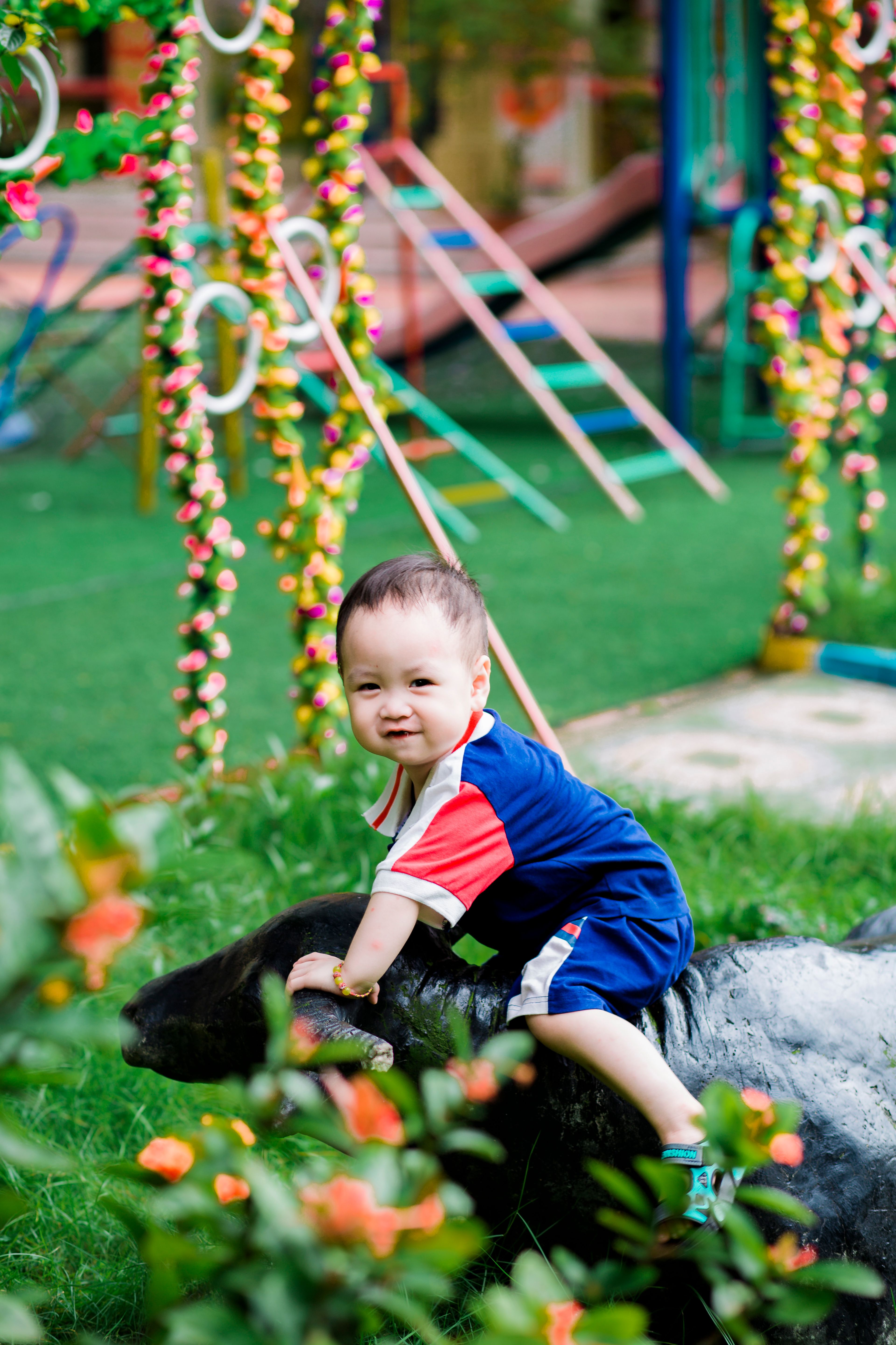 Cute boy playing on a sculpture in a colorful garden playground, radiating joy and fun.
