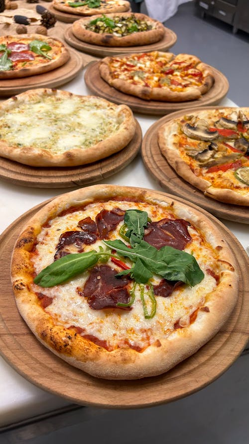 A variety of pizzas are on wooden trays