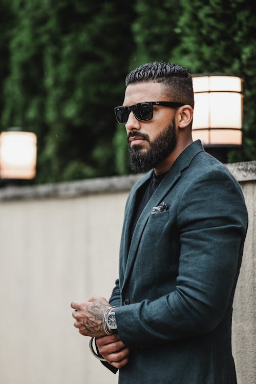 A man with a beard and sunglasses standing outside