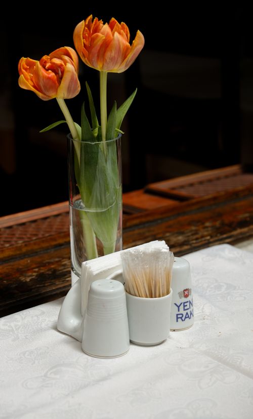 Free Orange tulips in a glass vase on a table with condiments. Stock Photo