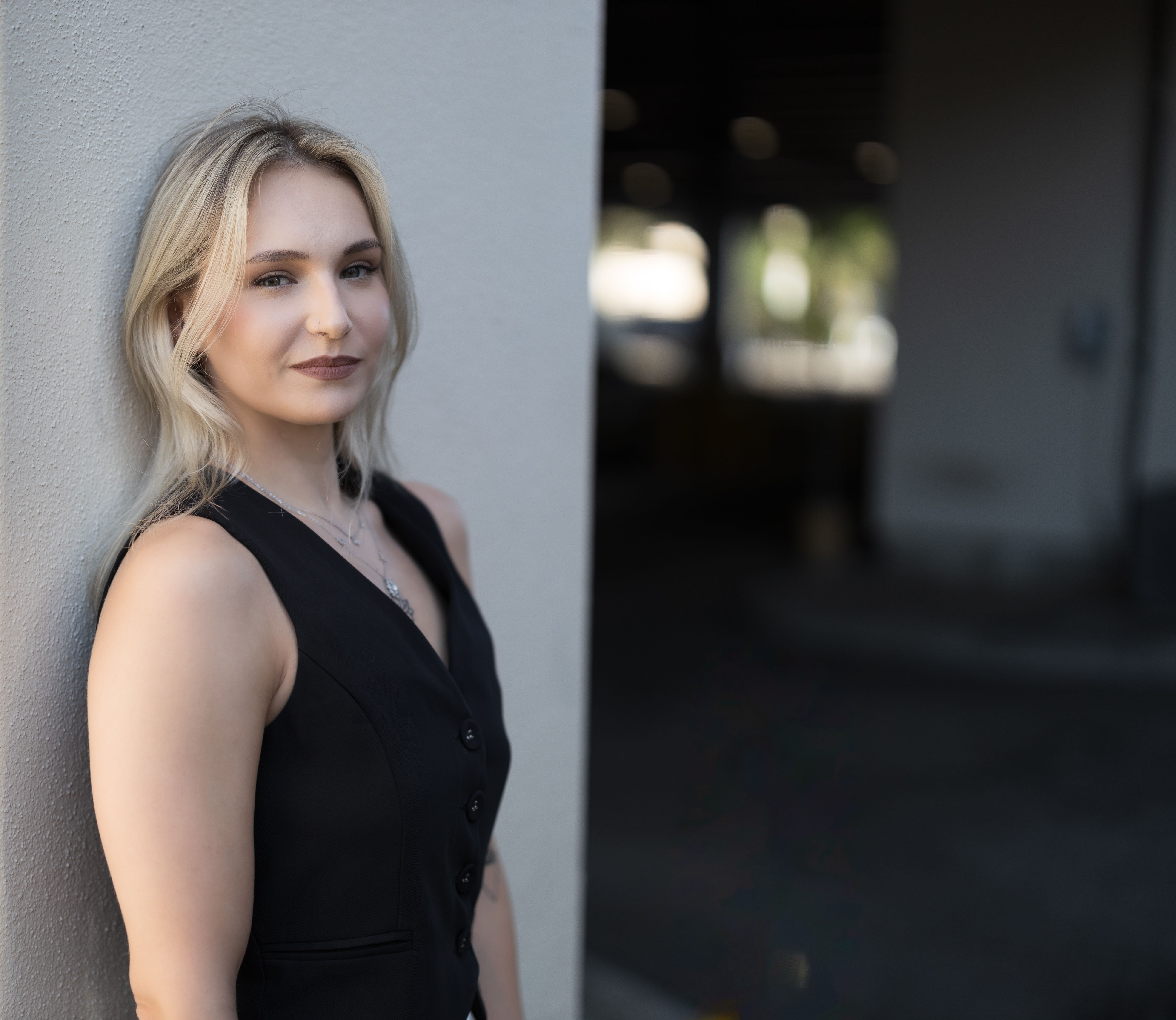 A fashionable woman posing confidently against a wall in Winter Park, Florida.