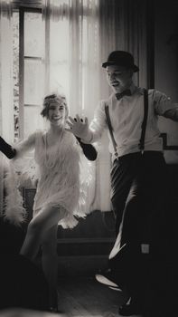 Black and white photo of a couple dancing in 1920s flapper fashion.
