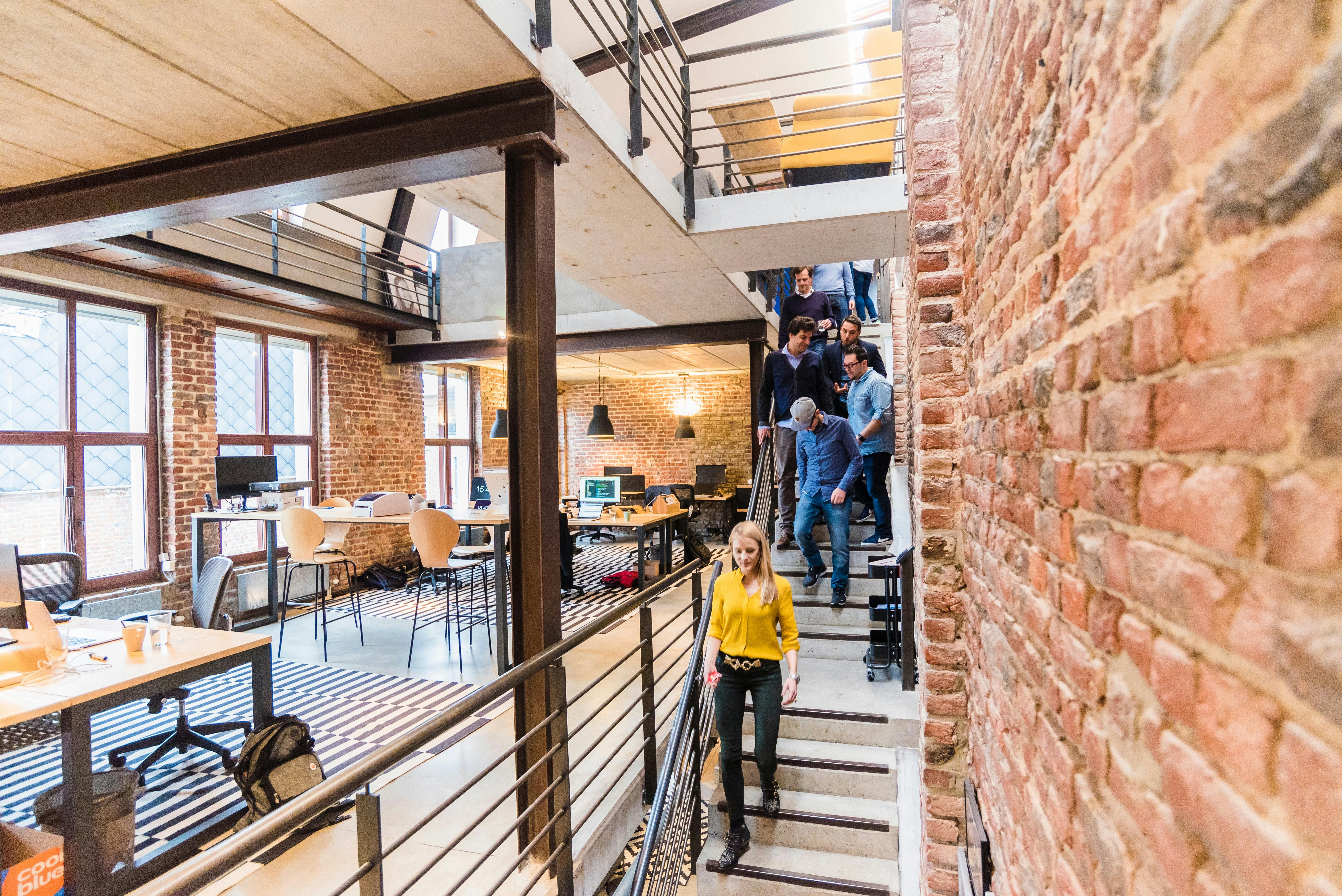 photo of woman in yellow top walking down stairs in a office room