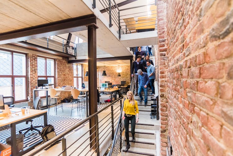 Photo Of Woman In Yellow Top Walking Down Stairs In A Office Room