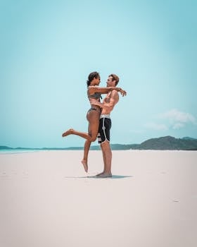 A couple enjoys a romantic moment on a sunny Whitsundays beach, Australia.