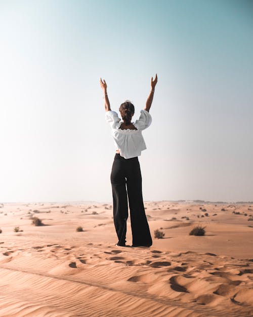 Foto Da Vista Traseira De Uma Mulher Com As Mãos Ao Alto, Em Pé Na Areia Do Deserto