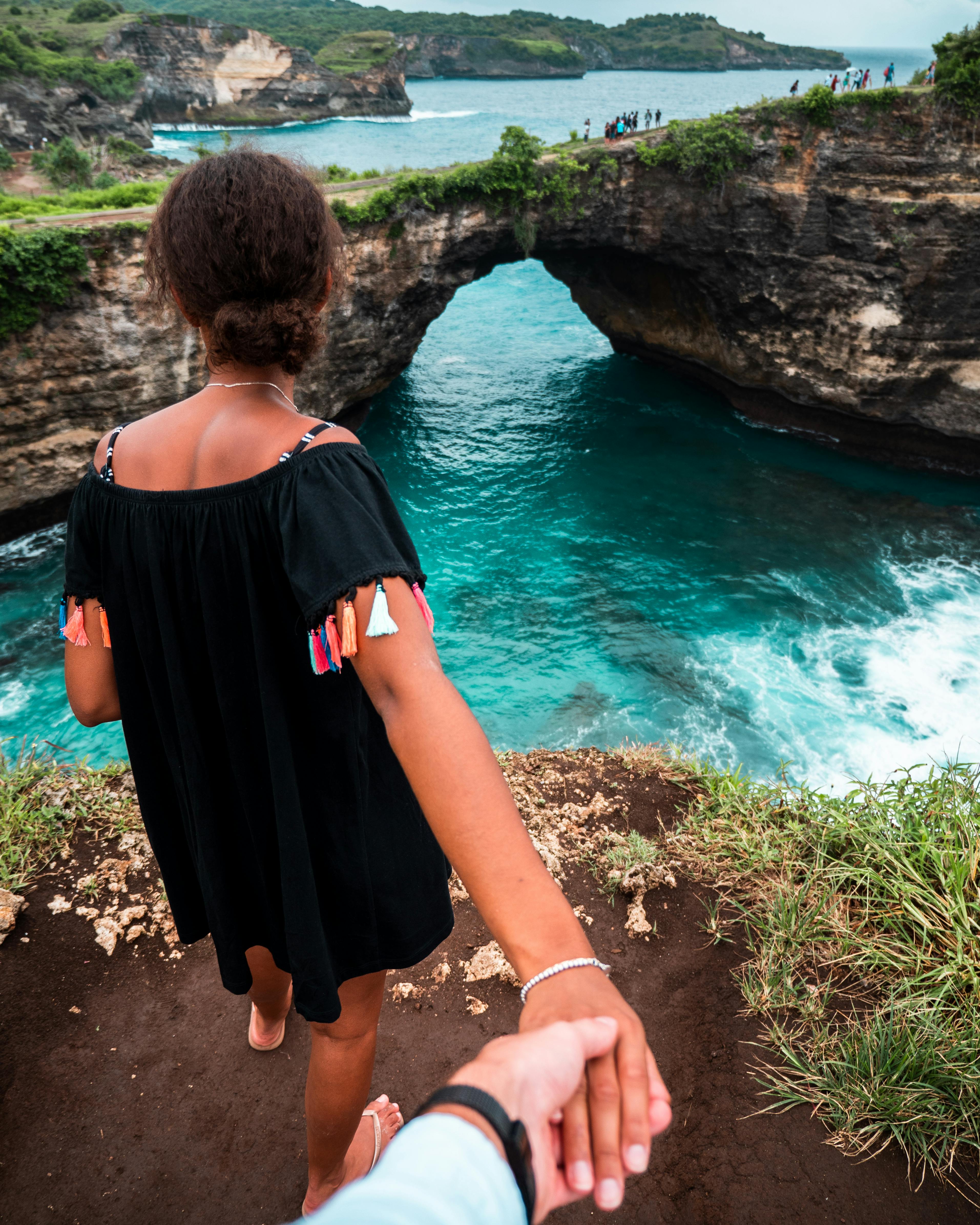 person holdings woman hand in front of body of water