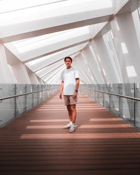 一个人在迪拜的当代玻璃走廊里，摆出姿势，走廊带有几何图案