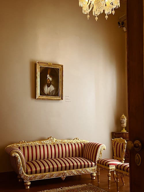 A room with a gold and red couch and a painting