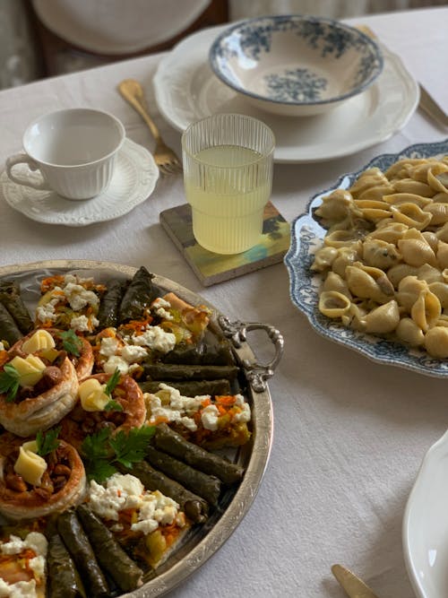 A table with plates of food and a bowl of pasta