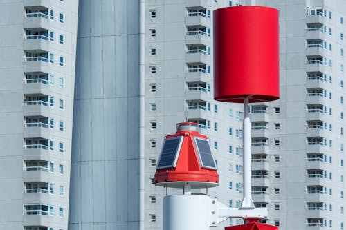 A red and white wind vane in front of tall buildings