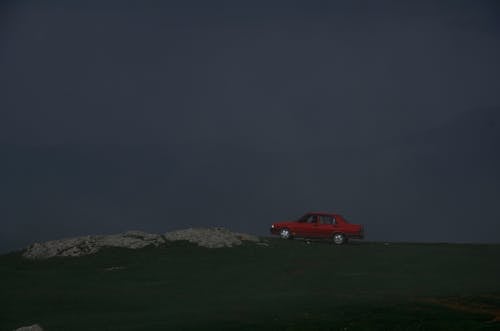 紅色轎車的照片停在草地上，背景為霧山