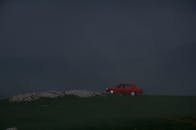 雾蒙蒙的山顶上，一辆红色的汽车孤零零地停在漆黑的天空下