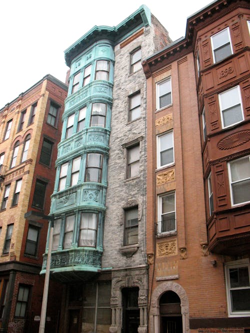 Teal and Brown Concrete Buildings Under Cloudy Sky