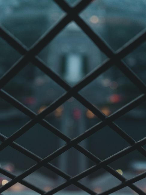 A close-up shot of a blurred chain link fence, capturing the pattern and depth of field.