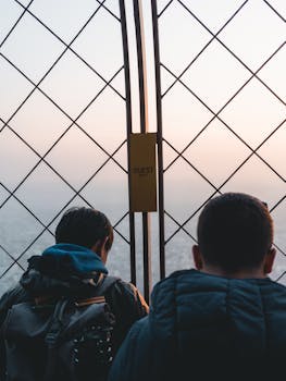日落时分，两名男子在巴黎埃菲尔铁塔上欣赏风景