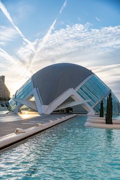 Beautiful architectural design of L'Hemisfèric in Valencia with a reflection in the water under a bright sky.