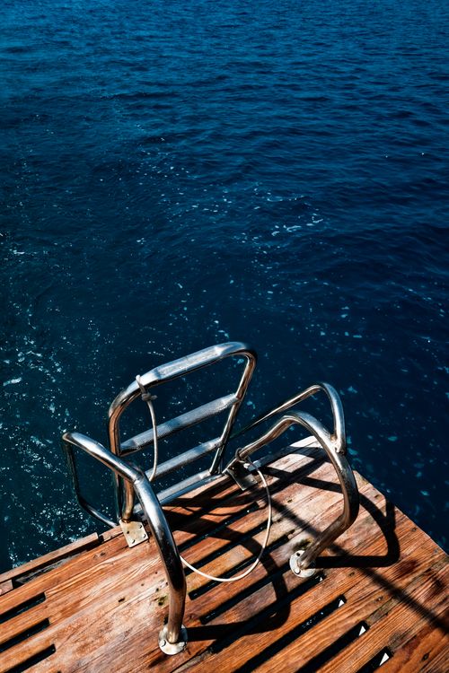 Free A metal ladder on a wooden pier leads into the deep blue waters of Antalya, Türkiye. Stock Photo