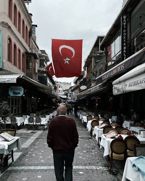 A man walking down a street with a turkey flag