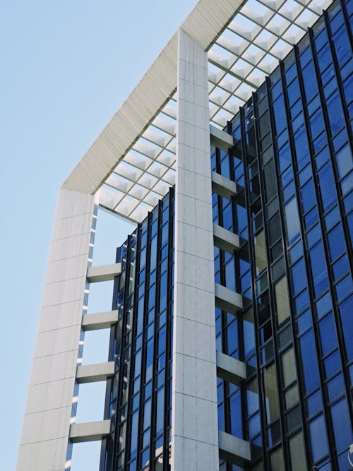 A tall building with a glass facade and a blue sky