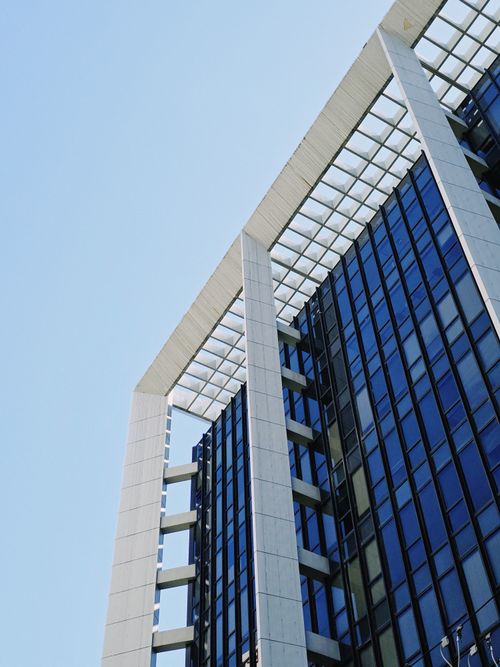 Free A striking view of a modern skyscraper with a sleek glass facade against a clear blue sky. Stock Photo