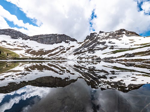 A mountain range with snow covered peaks and water