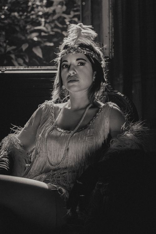 Free Vintage black and white portrait of a woman in 1920s flapper attire, featuring elegant fringe and pearls. Stock Photo