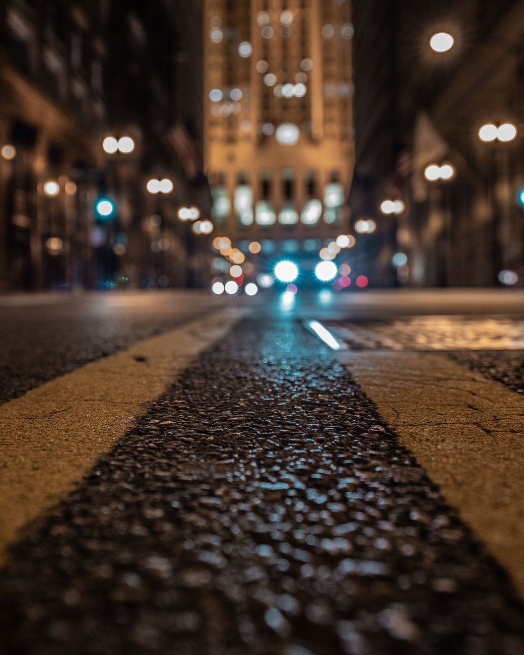 Low-angle view of a city street at night with bokeh lights enhancing the urban ambience.