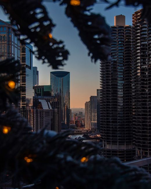 A breathtaking view of a city's skyscrapers and skyline during dusk, framed by festive lights.