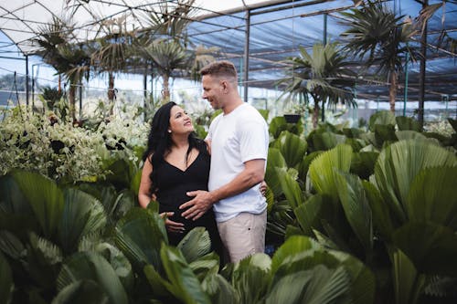 A pregnant couple standing in a greenhouse
