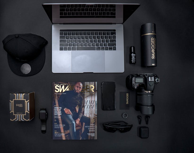 Flat lay of laptop, camera, magazine, and accessories with a modern aesthetic.