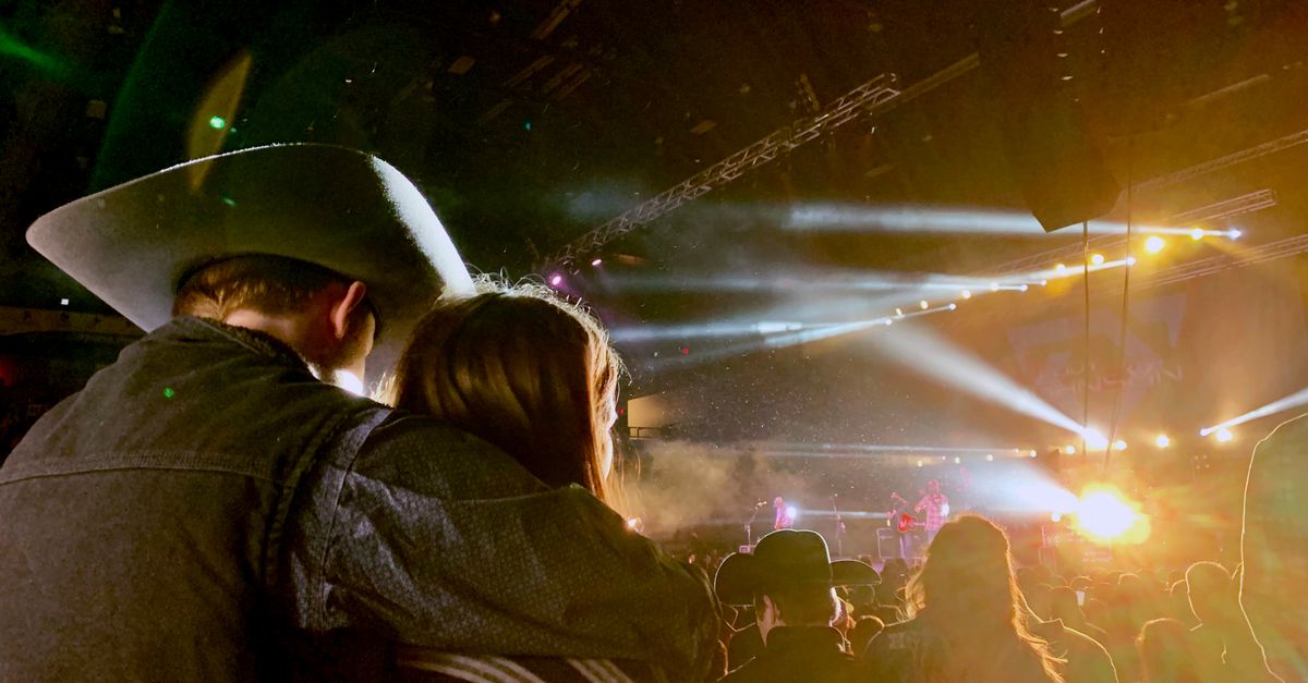 Couple enjoying a vibrant live country concert under bright stage lights.